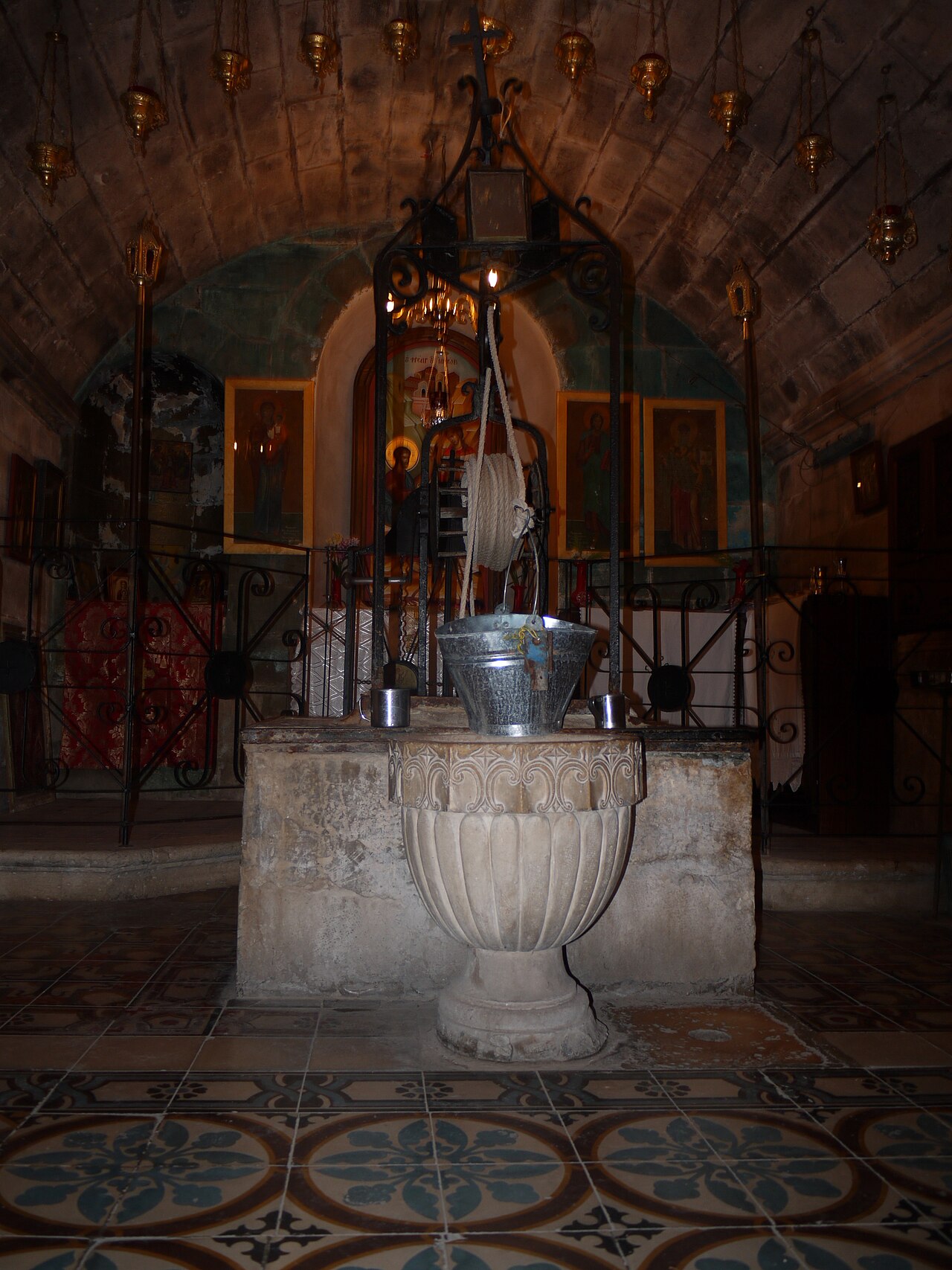 Jacob's Well today, an ancient stone well shaft inside a church, with a bucket on a rope descending into deep water.
