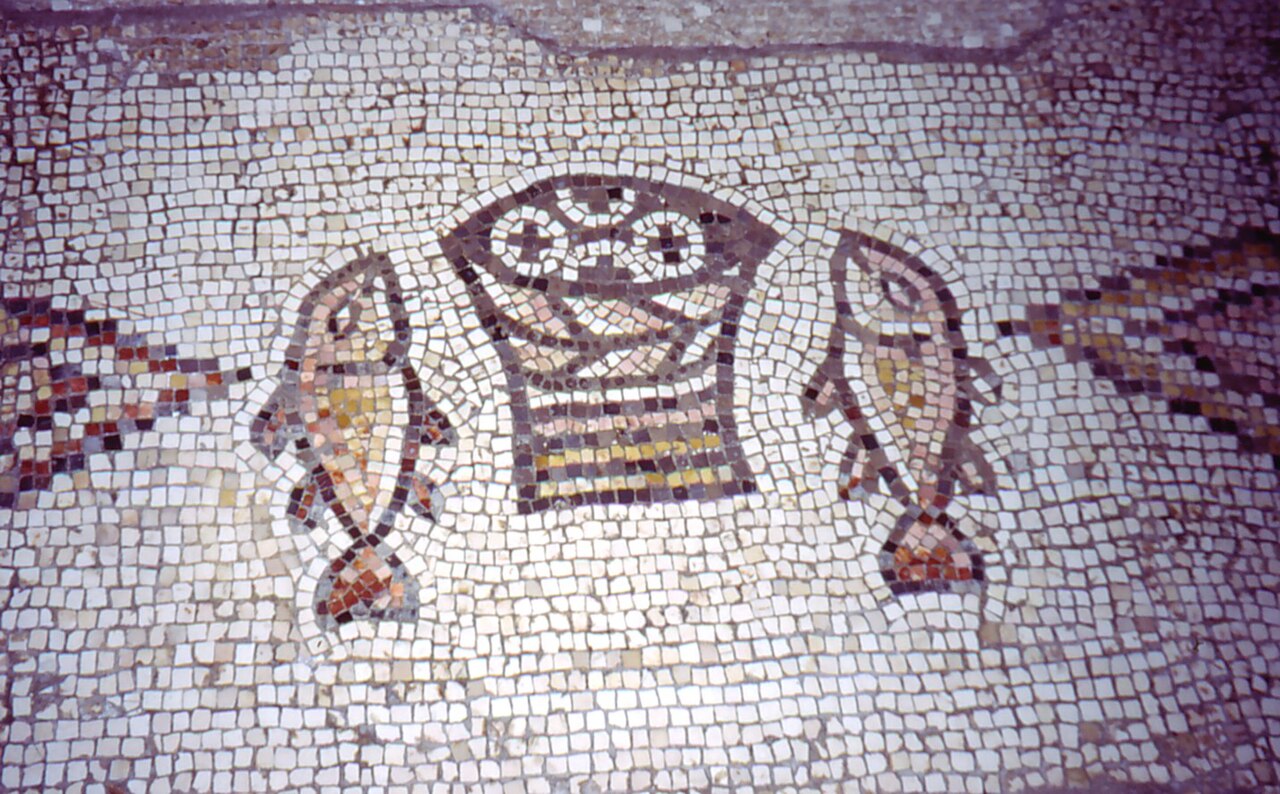 An ancient mosaic floor showing a basket of loaves flanked by two fish, from the Church of the Multiplication at Tabgha.