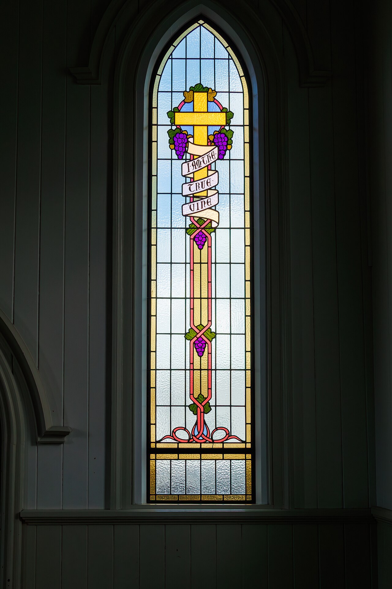 A stained-glass window depicting Christ as the true vine, branches and grapes radiating from him.